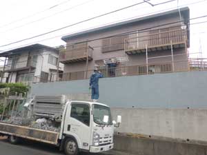 道路に止めてある足場の部材が満載のトラックから荷揚げの運び